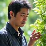 植物学とガーデニングに詳しい専門講師のKENJIが、庭で植物を観察しているポートレート